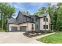 Modern two-story home with gray and beige siding, three-car garage, dark trim, and professional landscaping at 130 Nova Ln, Roswell, GA 30075