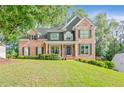 Charming two-story brick home with a covered front porch and a meticulously manicured lawn at 2073 Woodside Park Dr, Woodstock, GA 30188
