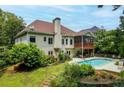 A backyard featuring a swimming pool, covered porch, and lush landscaping at 635 Piping Rock Pt, Lawrenceville, GA 30043