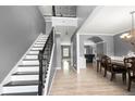Inviting foyer features a staircase with dark railing, wood floors, and dining area at 143 Monarch Way, Hiram, GA 30141