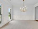 Spacious dining room with a decorative chandelier, large windows and wainscoting at 5865 Trailwood Ct, Suwanee, GA 30024