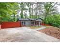 A cozy single-story home with gray siding, a red privacy fence, a covered porch and a long driveway at 3479 Thompson Dr, Atlanta, GA 30331