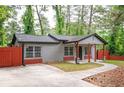 A cozy single-story home with gray siding, a red privacy fence, a covered porch and a driveway at 3479 Thompson Dr, Atlanta, GA 30331