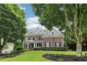 Attractive brick home with black shutters, a landscaped yard, and a partial view behind mature trees at 4085 Hillcrest View Ct, Suwanee, GA 30024