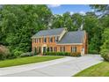 Elegant brick home with a lush green lawn, long driveway, and surrounded by mature trees at 5524 Wedgewood Sw Ct, Lilburn, GA 30047