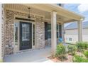 Inviting front porch with brick columns and charming seating area with plants at 171 Osier Dr, Mcdonough, GA 30252