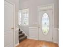 Inviting foyer with hardwood floors, white trim, glass front door, and staircase at 180 Mirramont Lake Dr, Woodstock, GA 30189