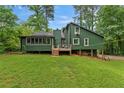 View of the backyard with green siding, wooden deck and lots of lawn at 1033 Justice Nw Ln, Acworth, GA 30102