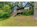 Two-story house with a wooden deck and stairs, surrounded by mature trees and greenery at 1033 Justice Nw Ln, Acworth, GA 30102