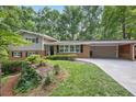 Attractive home featuring a well-maintained lawn, lush landscaping, and a spacious driveway leading to a carport at 225 River Springs Dr, Sandy Springs, GA 30328
