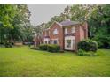 Two-story brick home with lush green lawn and mature trees at 214 Jamestown Ave, Jonesboro, GA 30236