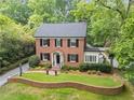 Charming two-story brick home with lush landscaping, a manicured lawn, and mature trees at 905 Stovall Ne Blvd, Atlanta, GA 30319