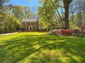 Traditional brick home featuring a large front lawn, mature trees, and beautiful landscaping at 905 Stovall Ne Blvd, Atlanta, GA 30319