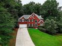 Two-story brick home with a long driveway, beautiful lawn, and surrounded by lush trees at 1850 Noblin Ridge Way, Duluth, GA 30097