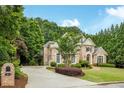 Stately brick home with mature trees, lush landscaping, and a circular driveway at 314 Caruso Ct, Sandy Springs, GA 30350