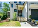 Close up of a home's front door with a brick walk-up, wrought iron railings, and mature landscaping at 2235 Birchtree Way, Marietta, GA 30062