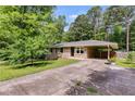 Charming single-story brick house featuring a covered driveway, lush trees, and a manicured lawn at 2575 Dobbs Nw Dr, Kennesaw, GA 30152