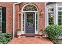Inviting front door with transom window, flanked by sconces and potted plants at 4020 Devereux Chase, Roswell, GA 30075