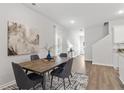 Elegant dining area features a wood table with gray chairs, modern art, and a view into the home's entryway at 6001 Pine Bluff Pl, Conyers, GA 30013