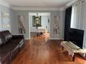 Cozy living room with hardwood floors, comfortable leather sofa, and open doorway to the dining room at 1159 Aurora Ct, Atlanta, GA 30338