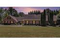 Charming brick home with a well-maintained lawn and mature trees under a colorful sky at 1935 Northbrooke Ln, Dunwoody, GA 30338