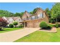 Attractive home showcasing a well-kept lawn, mature trees, and a convenient three-car garage at 5613 Lancashire Ln, Cumming, GA 30041