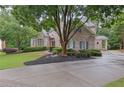 Beautiful brick home with a circular driveway, mature trees, and manicured landscaping at 415 Winn Park Ct, Roswell, GA 30075