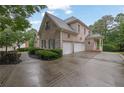 Side view of a brick home featuring a spacious three-car garage and well-maintained landscaping at 415 Winn Park Ct, Roswell, GA 30075