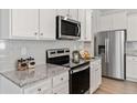 Well-equipped kitchen boasting white cabinets, granite countertops, stainless steel appliances, and modern fixtures at 6009 Pine Bluff Pl, Conyers, GA 30013