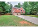 Charming two-story red brick home featuring a well-manicured lawn, attached two-car garage, and lush landscaping at 5765 Woodstone Dr, Cumming, GA 30028