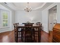 Formal dining room features a modern chandelier, hardwood floors, wainscoting, and a large window at 700 Mill Creek Cv, Canton, GA 30115