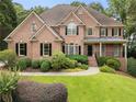Charming two-story brick home featuring a well-manicured lawn and mature landscaping at 10135 High Falls Pointe, Johns Creek, GA 30022