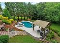 Backyard featuring a luxurious pool, hot tub, covered seating area, and lush landscaping for ultimate relaxation at 209 Breckenridge Ct, Canton, GA 30115