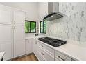 Contemporary kitchen has sleek white cabinetry, a modern range hood, and backyard views at 3430 Rocky Springs Ct, Marietta, GA 30062