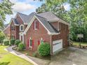 View of the side of the brick home showing the garage, lawn, and basketball court at 5190 Beech Forest Sw Dr, Lilburn, GA 30047