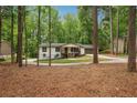 A charming home nestled among tall trees, featuring a long driveway, a covered porch, and fresh landscaping at 3455 Broxton Mill Way, Snellville, GA 30039