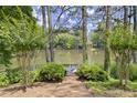 Scenic backyard view featuring a tranquil lake, wooden deck, and surrounded by lush greenery and mature trees at 3260 Kingshouse Commons, Johns Creek, GA 30022