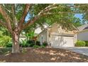 Single-Gathering home with a two-car garage, showcases mature trees, attractive landscaping, and manicured lawn at 4535 Vanadium Bnd, Cumming, GA 30040
