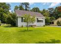Traditional single-story home featuring a lush green lawn, mature trees, and quaint architectural details at 8185 Rivertown Rd, Fairburn, GA 30213