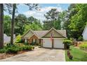 Well-maintained one-story brick home with a two-car garage, green lawn and mature tree coverage at 2080 Bankston Cir, Snellville, GA 30078