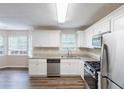 Modern kitchen featuring stainless steel appliances, granite countertops, white cabinets, and hardwood floors at 6590 Smoke Ridge Dr, Atlanta, GA 30349