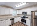 Well-lit kitchen featuring stainless steel appliances, granite countertops, white cabinets, and hardwood floors at 6590 Smoke Ridge Dr, Atlanta, GA 30349