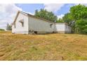 Angle showing the side of the house with an overgrown lawn in the foreground at 6191 Cumming Hwy, Canton, GA 30115