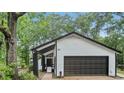 View of garage with black trim and white siding; surrounded by lush, mature trees at 6700 Knollwood Cir, Douglasville, GA 30135