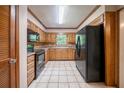 Well-lit kitchen with black appliances, tiled flooring, and light wood cabinetry at 5310 Arrowind Nw Rd, Lilburn, GA 30047