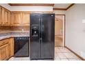 Close-up of a spacious kitchen with black appliances, tiled flooring, and light wood cabinetry at 5310 Arrowind Nw Rd, Lilburn, GA 30047