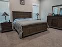 Cozy main bedroom featuring carpeted floors, a large bed with a wooden frame, and a matching dresser at 322 Woodridge Pass, Canton, GA 30114