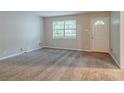 Inviting living room with plush carpeting, a large window, and a bright white door at 2045 Scarbrough Dr, Stone Mountain, GA 30088