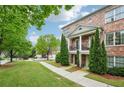 Brick townhome showcasing second story balconies, symmetrical evergreens, landscaped front yard and sidewalk entrance at 1858 Preserve Way, Atlanta, GA 30341