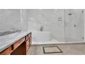 Luxurious primary bathroom showcasing a soaking tub, a glass enclosed shower and dual vanities at 1925 Stonewyck Ct, Cumming, GA 30041
